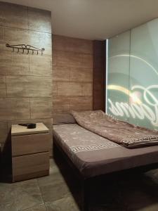 ein Schlafzimmer mit einem Bett und einer Holzwand in der Unterkunft Berić Rooms Hostel in Šabac