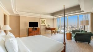 a bedroom with a bed and a desk and a television at Mövenpick Hotel Al Khobar in Al Khobar