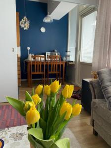 een vaas gevuld met gele bloemen in een woonkamer bij Hot spot of Vaasa with City Hall views in Vaasa
