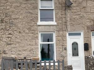un edificio de piedra con una puerta blanca y una valla en Quarryman’s Holiday Let, en Llysfaen
