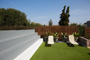 a backyard with a white fence and chairs and grass at Nur Villa in Karfas