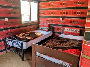 two beds in a room with red and green stripes at Wadi Rum Camp & Jeep Tour in Wadi Rum