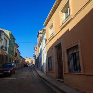 Caudete de las FuentesにあるCASA RURAL ALEGRÍAの道路に停車する建物と車が並ぶ空き道