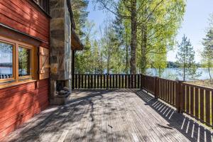 eine hölzerne Veranda eines Hauses mit einem Holzzaun in der Unterkunft Cozy cottage by the lake, Charlottenberg in Åmotsfors