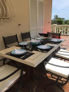 a wooden table with chairs and plates and wine glasses at Villa Manù B&B Chambre D'hote in Les Issambres