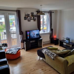 a living room with a couch and a flat screen tv at Driftmark Aberavon Beach The Crownlands 4 bedrooms Large Driveway parking 2 mins from Beach in Port Talbot