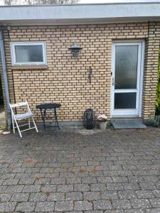 een tafel en een stoel voor een bakstenen gebouw bij Bed House By Me in Vester-Skerninge