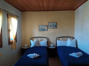 um quarto com 2 camas com lençóis azuis e uma janela em Aspri Villa em Ammoudia