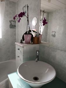 lavabo blanco en un baño con flores en un estante en Elise cornu, en Mantry