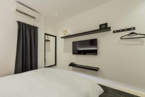 a white bedroom with a bed and a tv at STAYS HOTEL in Kuala Lumpur