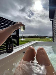 una persona bebiendo una copa de vino en una bañera de hidromasaje en Wild Hideaways Luxury Lodges and Eco Spa, en Bantry