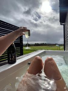 a person drinking a glass of wine in a hot tub at Wild Hideaways Luxury Lodges and Eco Spa in Bantry