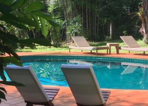 two lounge chairs sitting next to a swimming pool at Sang Tong Huts in Mae Hong Son