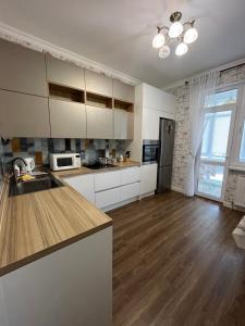 eine Küche mit weißen Schränken und Holzböden in der Unterkunft 2-х комнатная квартира в ЖК Заман in Atyrau