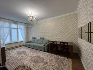 ein Wohnzimmer mit einem Sofa und einem Tisch in der Unterkunft 2-х комнатная квартира в ЖК Заман in Atyrau