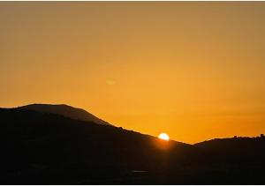 una puesta de sol con la puesta de sol detrás de una montaña en Moranit, en Moran