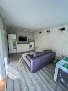 sala de estar con sofá púrpura y TV en Apartament by Wyszyńskiego Street en Konin