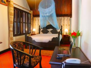 a bedroom with a bed and a desk with a laptop at Namkhan View Luangprabang Resort in Luang Prabang