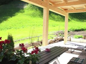 a wooden pergola with a picnic table and red flowers at Charming Apartment in Kirchberg in Tirol with Private Garden in Kirchberg in Tirol