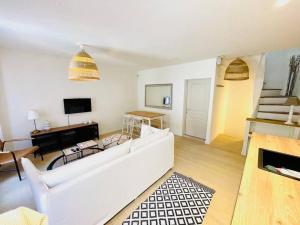 a living room with a white couch and a piano at Maison charmante avec terrasse, 2 chambres in Marseillan