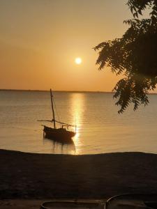 ein Boot, das bei Sonnenuntergang im Wasser sitzt in der Unterkunft Matumaini Guest House in Migogoni