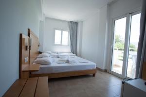 a white bedroom with a bed and a large window at Kos Bay Hotel in Kos Town