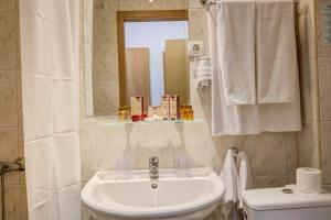 uma casa de banho com um lavatório, um WC e um espelho. em Kini Park Hotel All Inclusive & Free Parking em Golden Sands