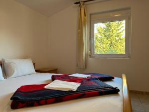 a bed with a blanket on it with a window at Apartments and Room MV in Petrovac na Moru