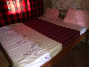 a small bed with a red and black checkered sheet at Kiharas Farm stay in Nairobi