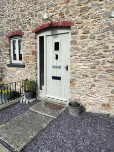 una puerta blanca en el lateral de un edificio de piedra en Acorn Cottage, en Ross-on-Wye