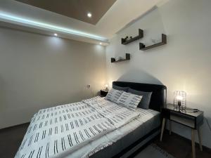 1 dormitorio con cama blanca y cabecero negro en Apartman Central A&D, en Bečej