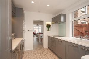 a kitchen with gray cabinets and a sink and a window at Clermont, Ruskin Rd in Ipswich