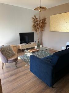 a living room with a blue couch and a tv at Pavillon d'Éole in Berck-sur-Mer