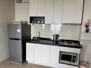 a kitchen with white cabinets and a refrigerator at The Base Infinity in Pattaya Central