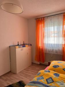 1 dormitorio con 1 cama y una ventana con cortinas de color naranja en Handwerker- & Monteur- & Gästezimmer, en Rosenfeld
