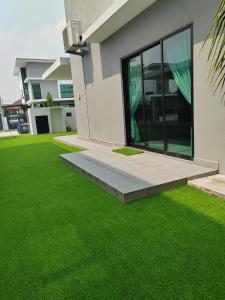 una casa con un césped verde delante de ella en Five BEDROOMS RESIDENTIAL HOME WITH FREE WIFI en Sepang