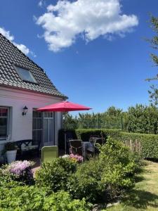 Dunsum的住宿－Deichhof Whg 23，房屋设有带红色遮阳伞的庭院