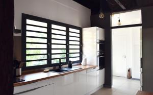 eine Küche mit weißen Schränken, einem Waschbecken und einem Fenster in der Unterkunft Villa Paul Ermitage in La Saline-Les-Bains