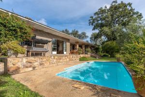a swimming pool in front of a house at Tygerfontein Safari Villa in Amakhala Game Reserve