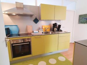 Elle comprend une petite cuisine avec des placards jaunes et un évier. dans l'établissement Ferienwohnung INA am Bodensee mit Schwimmbad und Sauna, à Uhldingen-Mühlhofen