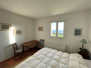 1 dormitorio con cama, escritorio y ventana en Maison de pêcheur vue mer exceptionnelle, en Audinghen