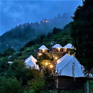 ein Resort mit Zelten auf einem Hügel in der Nacht in der Unterkunft The Bugyal in Kanatal