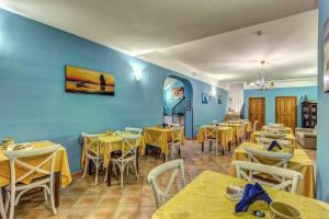 a restaurant with yellow tables and chairs and blue walls at Hotel Nice in Sorrento