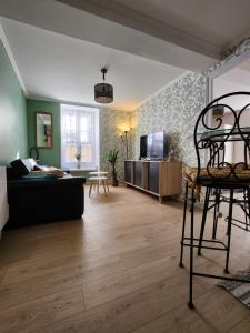 ein Wohnzimmer mit einem Sofa und einem TV in der Unterkunft Le p'tit gîte d'Edmé in Montbard