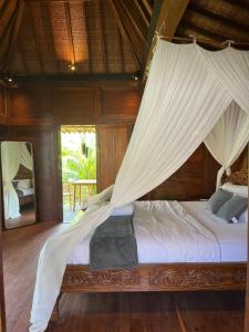 a bedroom with a bed with mosquito netting at Kaiwatu House in Ubud