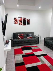 克羅伊登的住宿－Attractive 2 bed apartments free Wi-Fi and parking，客厅配有沙发和红黑地毯。