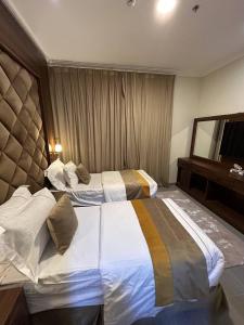 a hotel room with two beds and a mirror at الاتحاد الذهبية للشقق المخدومة 3 in Al Hofuf