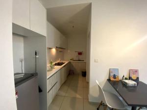 una cocina con armarios blancos, una mesa y una barra en The Stay Guest House @ Kenwingston Residence en Cyberjaya