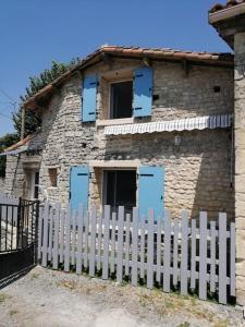 a white fence in front of a stone house at Gîte Bin Benaise draps et serviettes compris in Pamproux