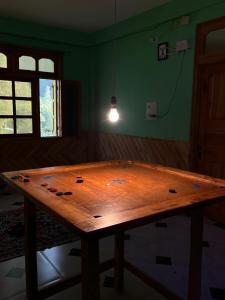 een houten tafel in een kamer met een licht bij Ohana cafe & homestay in Kasol